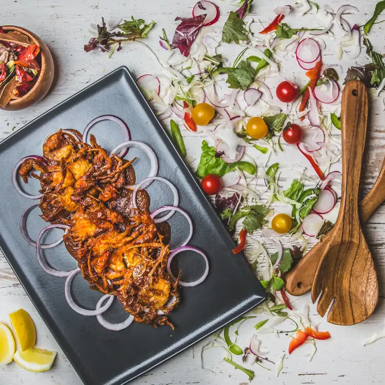 A pakora curry dish with onions and salad at Asha’s Birmingham, one of the best date night restaurants in Birmingham.