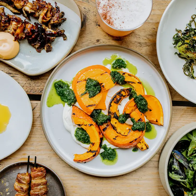 Vegan flatbreads with red peppers, greens, and vegan cheese, served with grilled peppers and olives at The Anthologist, one of the best vegan restaurants in Manchester.