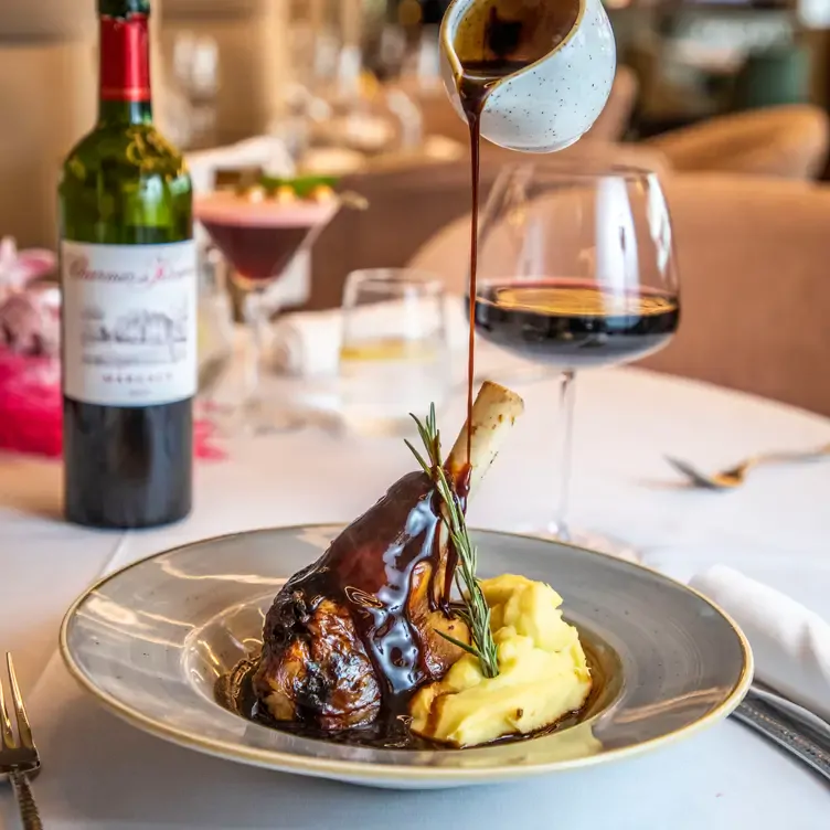 A waiter pours gravy over a roasted lamb shank and mashed potato dish at Noel’s Bar and Restaurant.