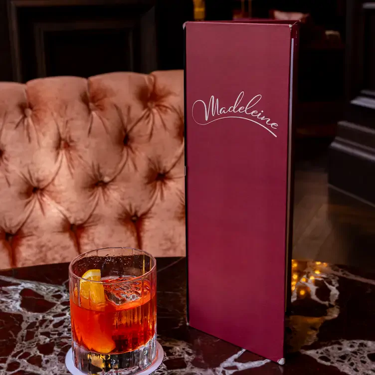 An Old-Fashioned cocktail beside a cocktail menu at The Madeleine Bar, one of the most romantic restaurants in Birmingham.