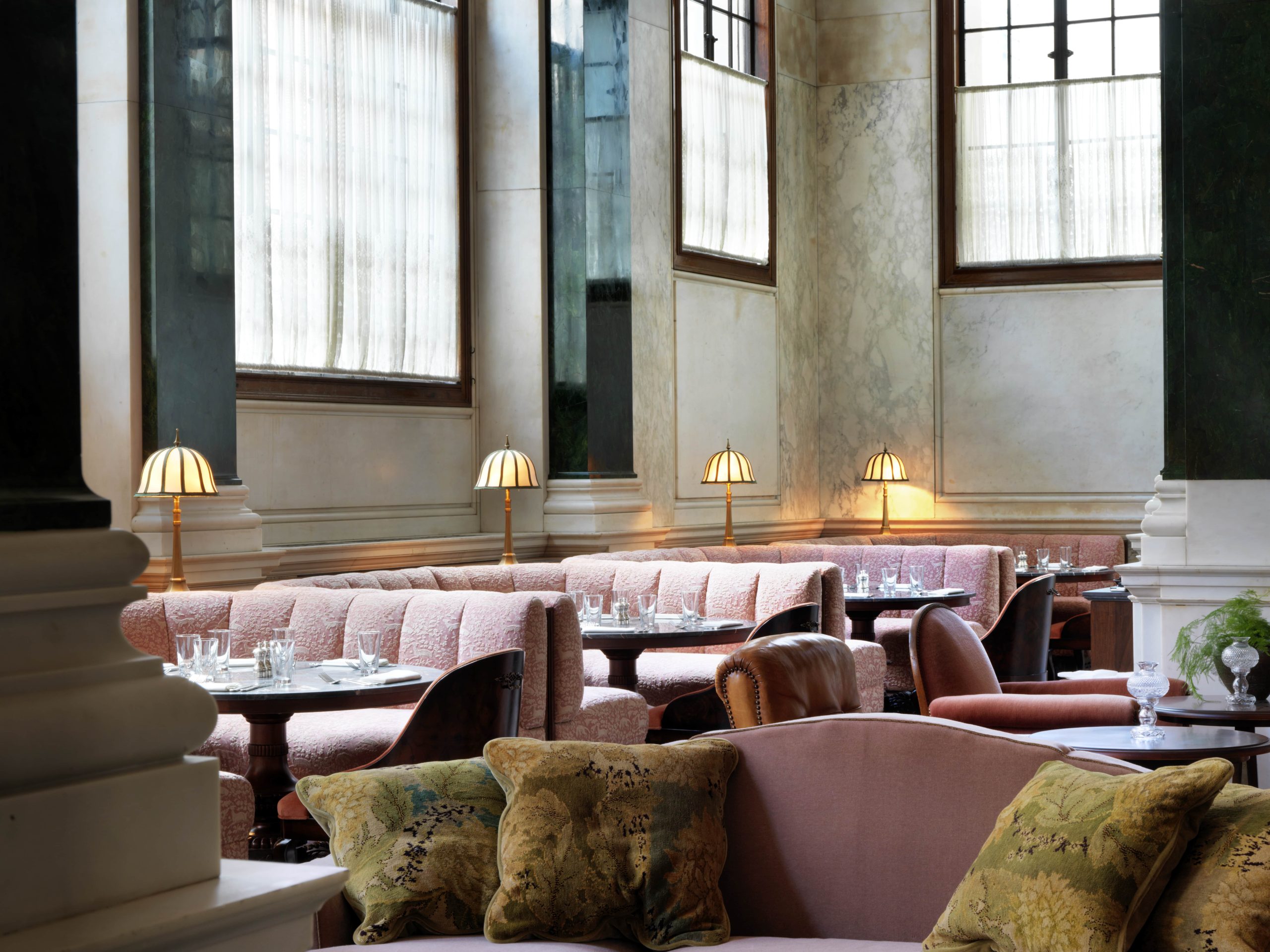 Pink velvety seating and low-lit interiors with high ceilings and windowns at Millie's Lounge restaurant at The Ned hotel, London