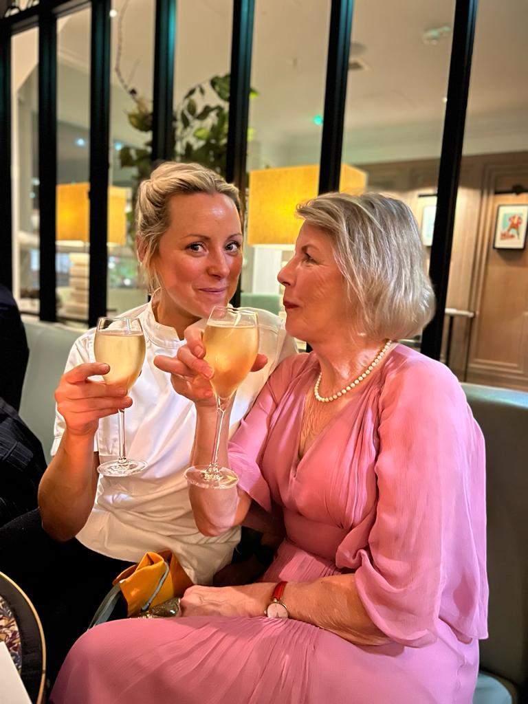 A female chef toasts with her mother who is wearing a pink dress.