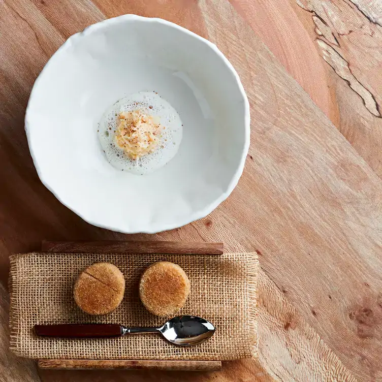 A white bowl sits on a raw wooden table at Restaurant St. Barts, one of the most sustainable restaurants in London and the UK.