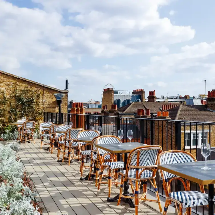 A rooftop terrace with tables and chairs lined up with views over London's roofs at Rucola at The Conduit, one of the best rooftop restaurants in London