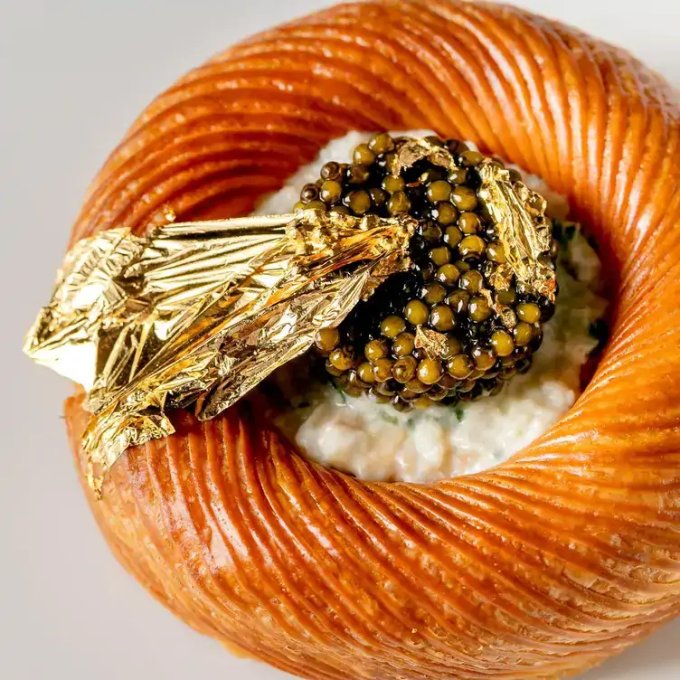 A round-shaped pastry dish filled with caviar and topped with golden leaves at Alex Dilling at Hotel Café Royal, one of the best restaurants in London