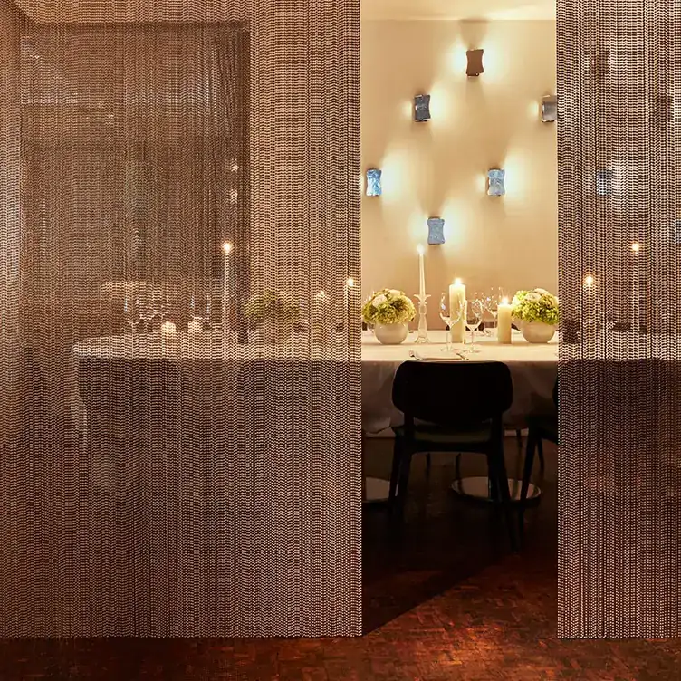 An elegant dining table adorned with candles and flowers behind two see-through curtains at Locanda Locatelli, one of the best fine dining restaurants in London