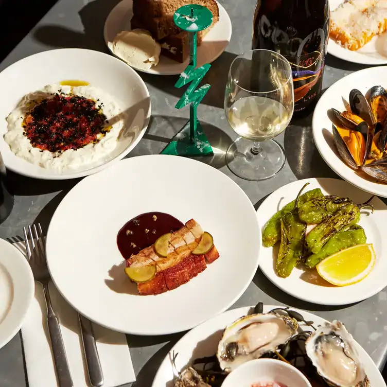 A spread of small plates featuring padrón peppers, bread, seafood, hummus and wine at Bar Crispin, one of the best outdoor wine bars in London