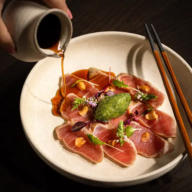 A diner pours sauce over a plate of tuna sashimi at Aqua Kyoto, one of the best Japanese restaurants in London for outdoor dining