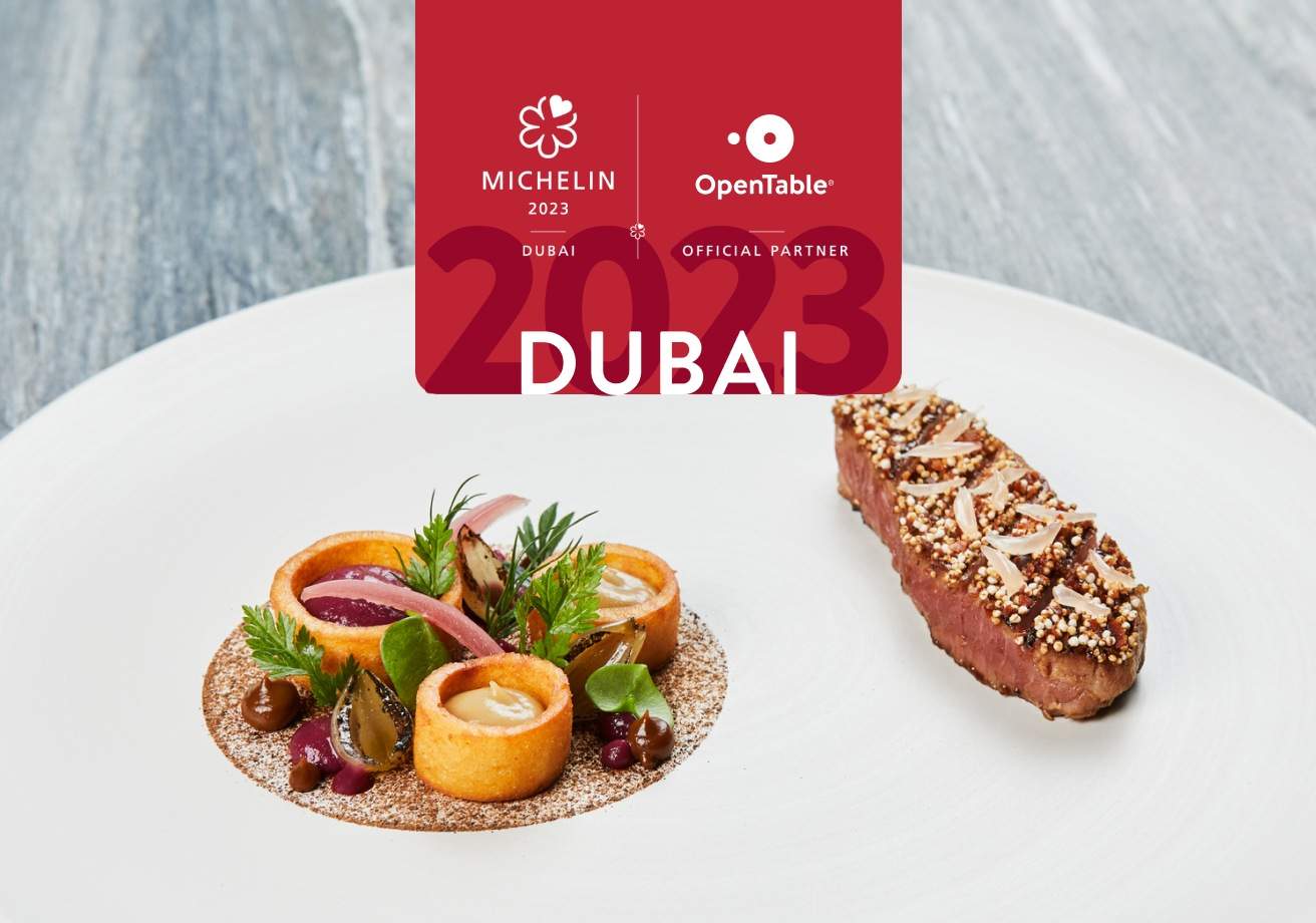 A white plate with composed pieces of food and a MICHELIN logo indicating this is the announcement for MICHELIN Bib Gourmand recipients in Dubai in 2023