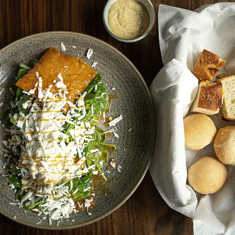 A salad topped with feta sits alongside a break basket and a dip at Géa, one of the best Greek restaurants in London