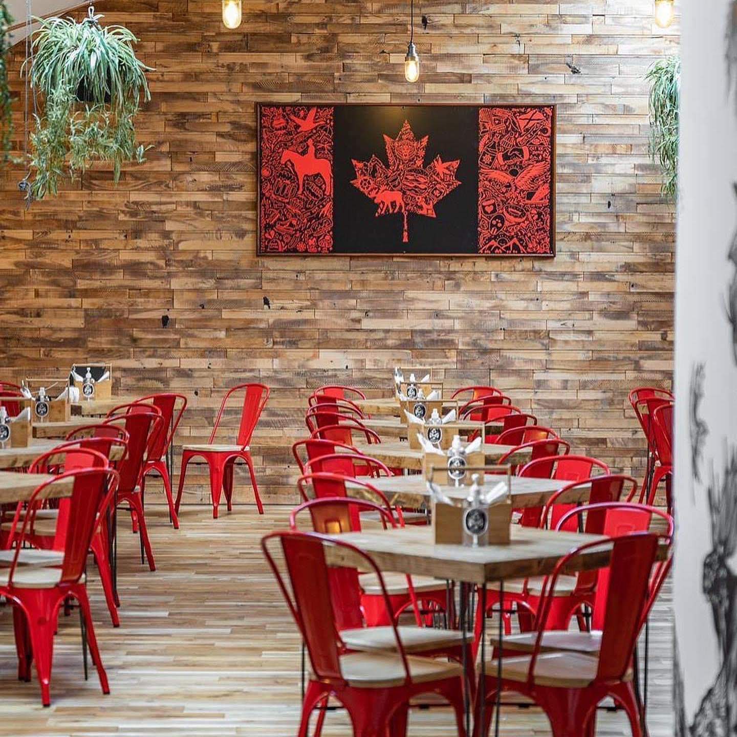 A large maple leaf print is mounted in a dining room filled with red chairs and wood pannelling at Down the Hatch, a restaurant in Edinburgh