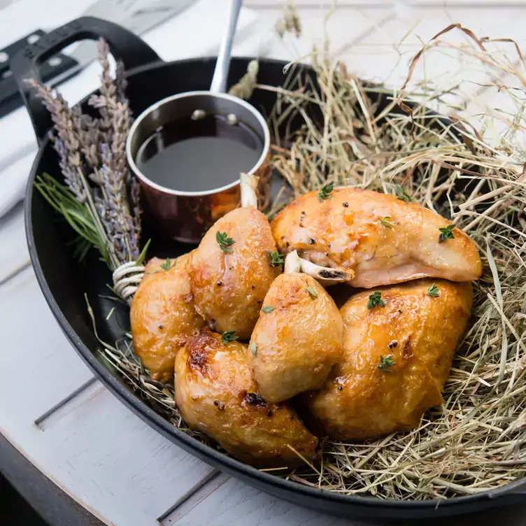 A basket of cooked chicken with a pan of sauce from the menu at Mercer Roof Terrace Igloos, one of the best restaurants for Christmas in London.