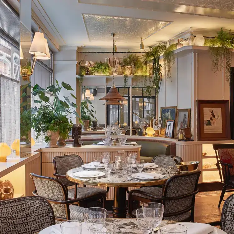 A dining area at Louie, one of the best restaurants for Christmas in London, with grey and white furnishings and lots of indoor plants.