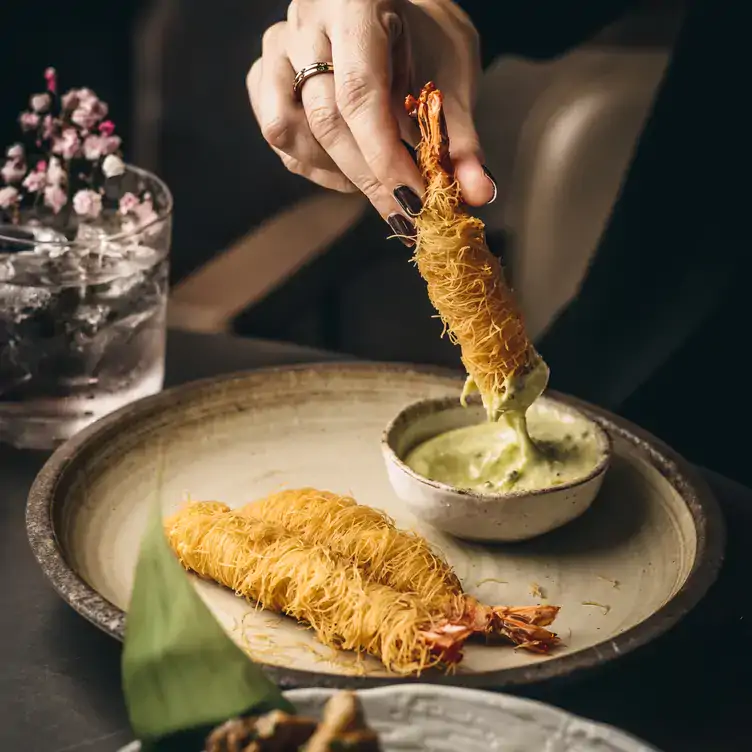 A diner dipping a tempura prawn into sauce at Bloomsbury Street Kitchen, one of the best festive restaurants in London.