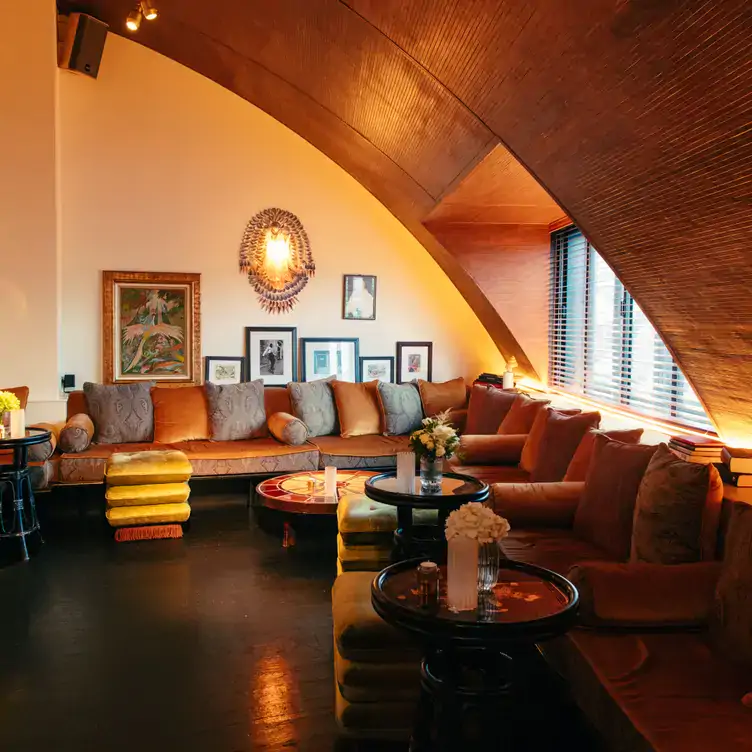 A relaxed dining area at Louie, one of the best festive restaurants in London, with sofas, low tables and a curved ceiling.