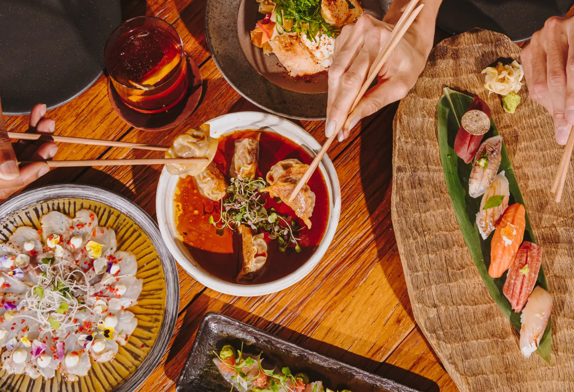 A spread of Asian dishes featuring gyozas and sashimis at a restaurant.