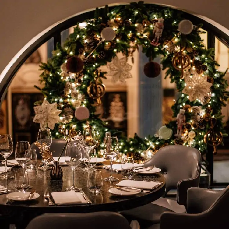 A table at Indigo at One Aldwych, one of the best Christmas restaurants in London, with leather seats, glassware and a festive wreath decoration.