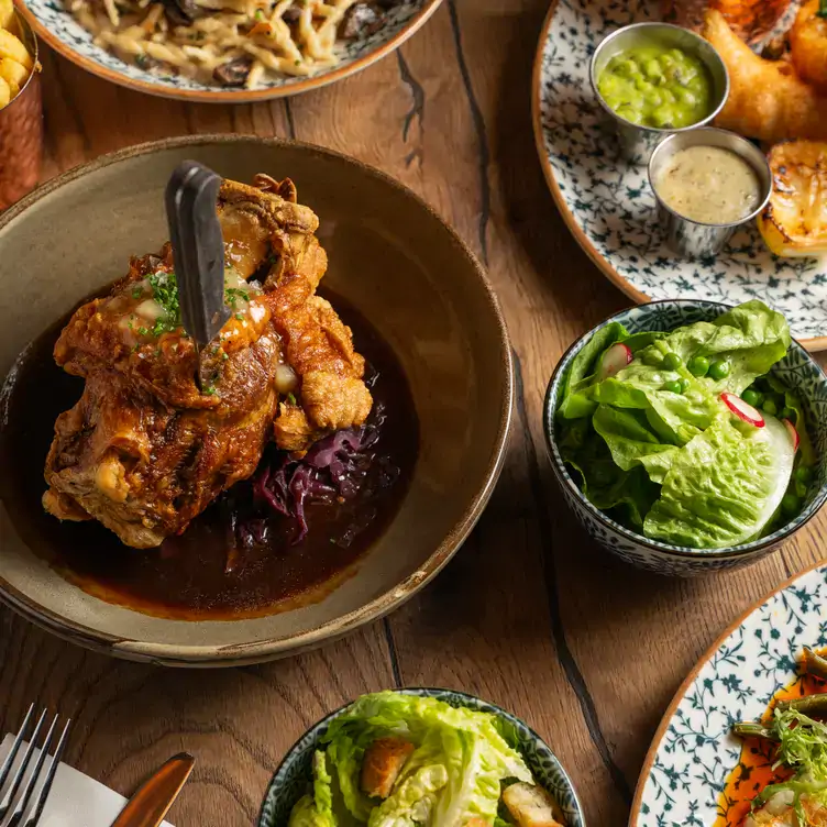 Several European main courses with salad bowls on a table at Albert’s Schloss, one of the best Christmas restaurants in London.