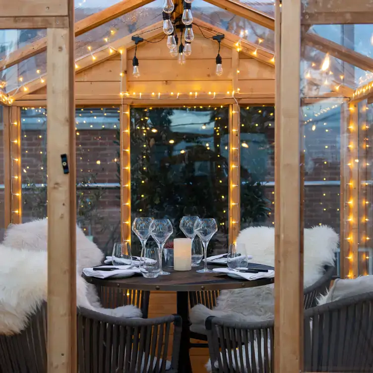 A cabin-style dining area with lights and blankets on each seat at Mercer Roof Terrace Igloos, one of the best festive restaurants in London.