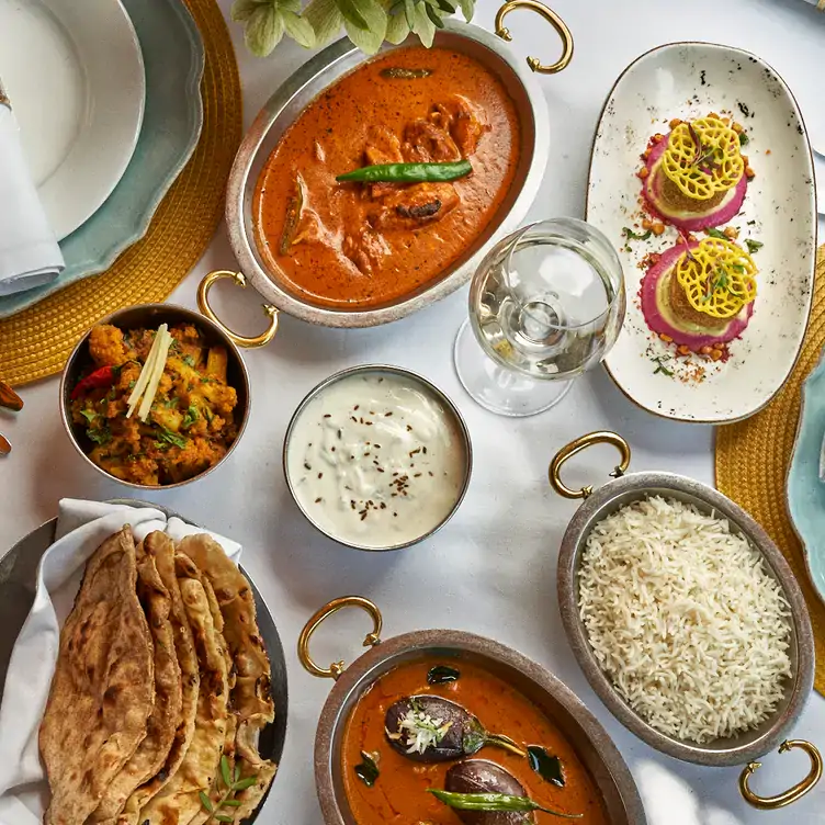 Curries, rice and Indian sides with wine and water on a table at Jamavar, one of the best London Christmas restaurants.