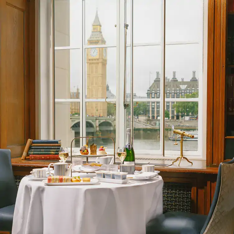 Afternoon tea on a white-clothed table by a window with a view of Big Ben at The Library at County Hall, one of the best Christmas restaurants in London.