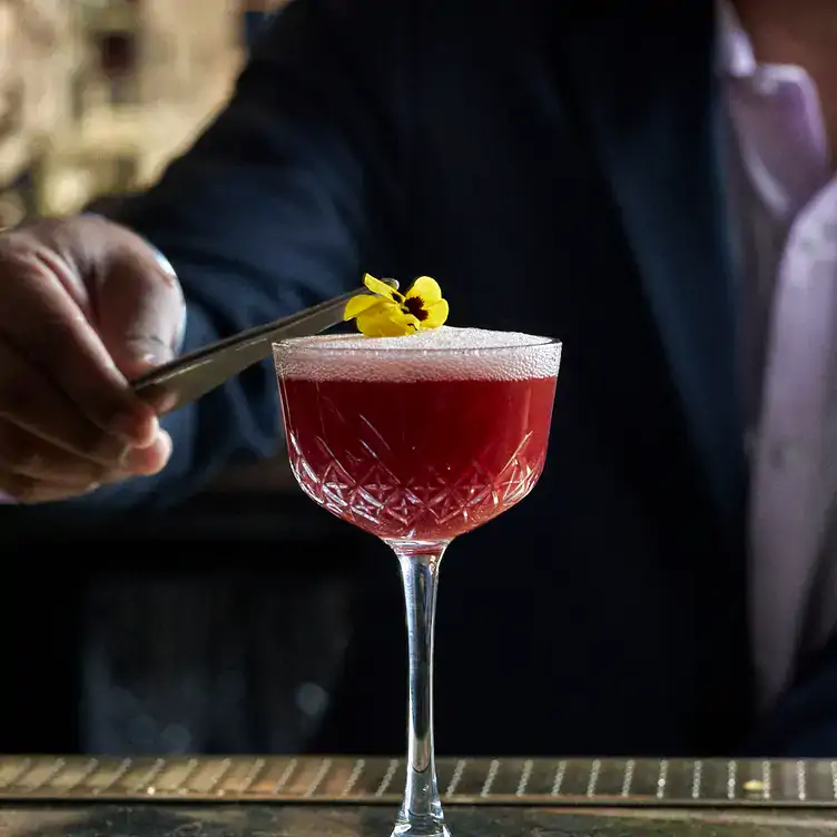 A flower is placed atop a red cocktail at Jamavar, one of the best Christmas restaurants in London.