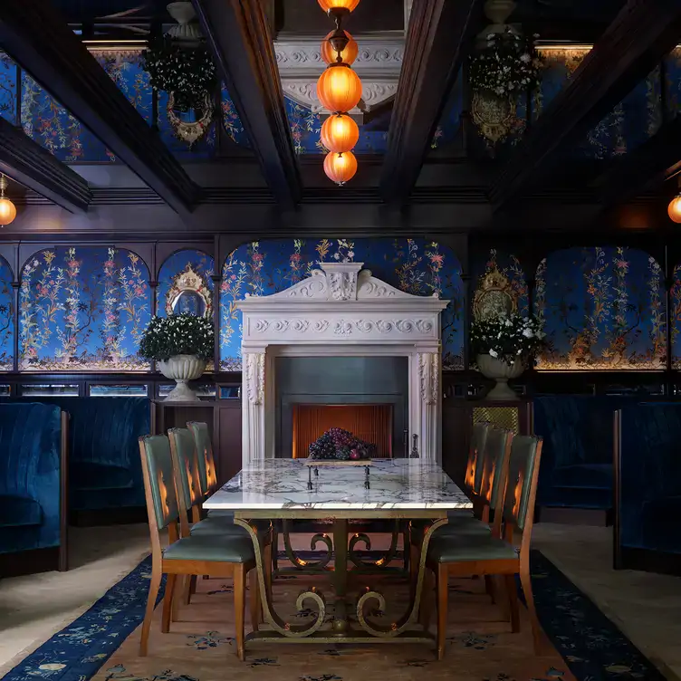 A marble table in the centre with booth seating to the side and a fireplace behind in the dining room at The NoMad London, one of the best Christmas restaurants in London.