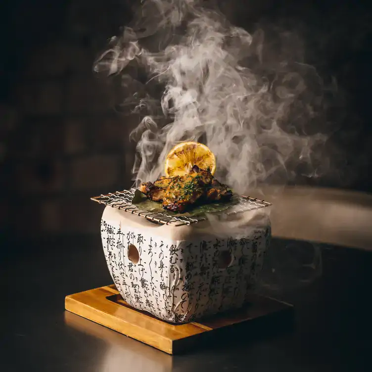 A meat dish served on a small grill over an ornamental bowl with steam rising at Bloomsbury Street Kitchen, one of the best London Christmas restaurants.