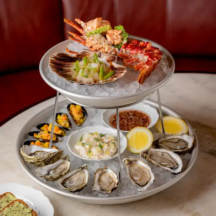 A tiered platter filled with ice and fresh seafood, with condiments and a side of bread, from the menu at The Midland Grand Dining Room, one of the best London Christmas restaurants.