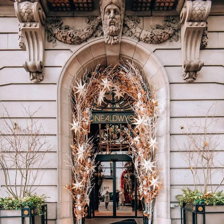 The entrance to Indigo at One Aldwych, one of the best restaurants for Christmas in London, with stars and Christmas tree decor around the doorway.