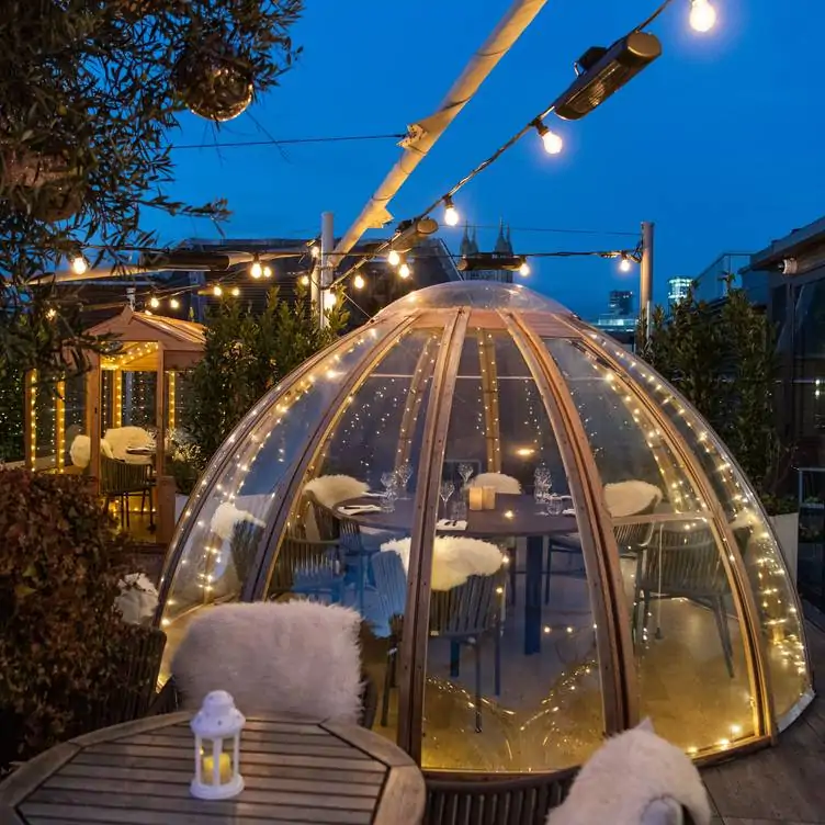 The rooftop dining area at Mercer Roof Terrace Igloos, one of the best London Christmas restaurants, with an illuminated igloo seating area and outdoor tables.