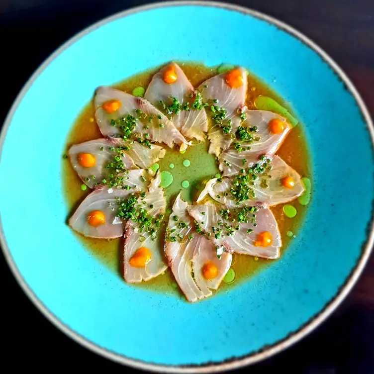 Thinly sliced carpaccio decorates a plate like a flower sitting in light soy sauce at Bamboo-Mat, one of the best sushi restaurants in London.