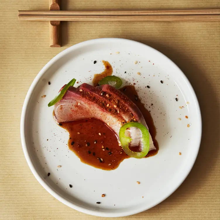 A well-presented plate of tuna sashimi in soy sauce sits on a white plate at TEMAKI, one of the best sushi restaurants in London.