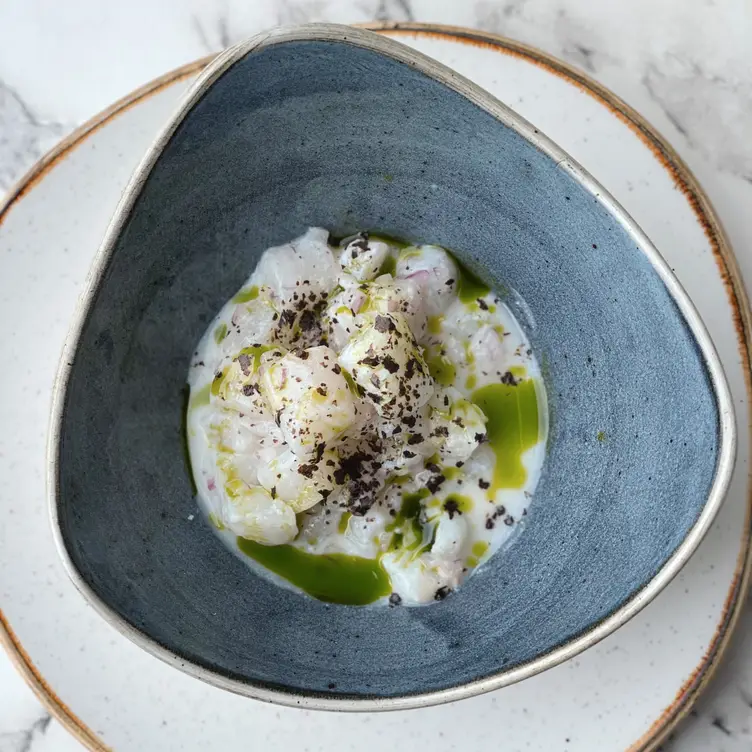 A colourful seafood dish with creamy white sauce in a blue bowl at The Melusine in London.