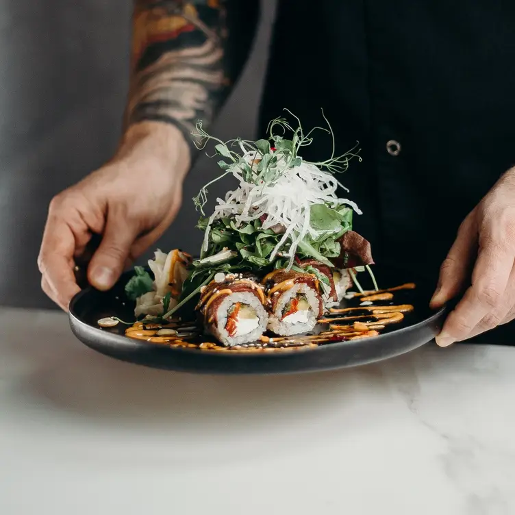 A man holds a plate of extravagantly presented sushi rolls at Bamboo-Mat, one of the best sushi restaurants in London.