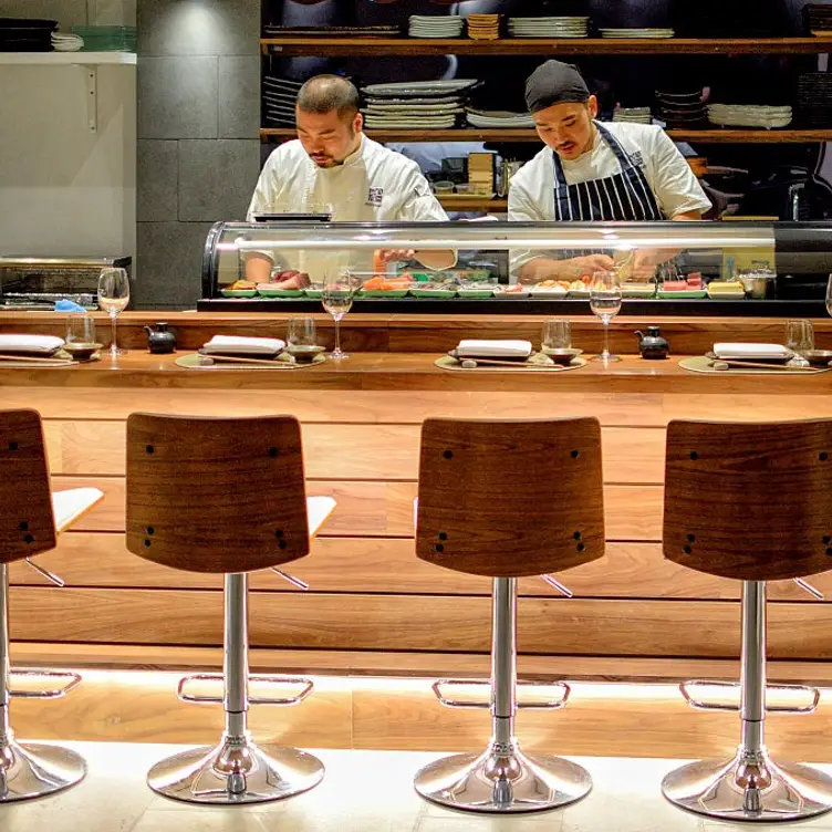 Two sushi chefs are busy preparing food behind the bar at Sushi Murasaki, one of the best sushi restaurants in London.