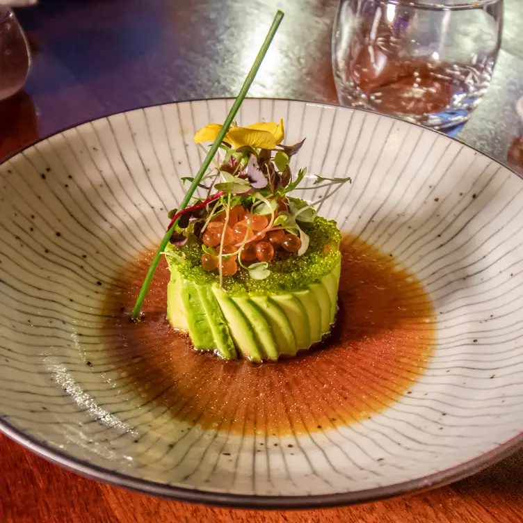 A stylish avocado-wrapped sushi sits on a plate in a shallow pool of soy sauce at Tsunami – Clapham, one of the best sushi restaurants in London.