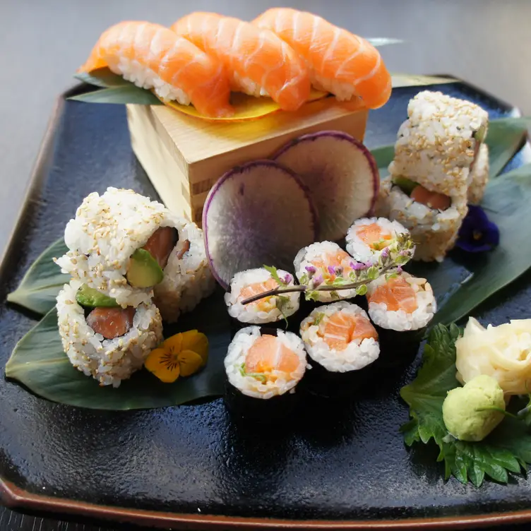 A neat arrangement of sushi rolls on leaves, placed carefully on a black plate at Sushi Murasaki, one of the best sushi restaurants in London.