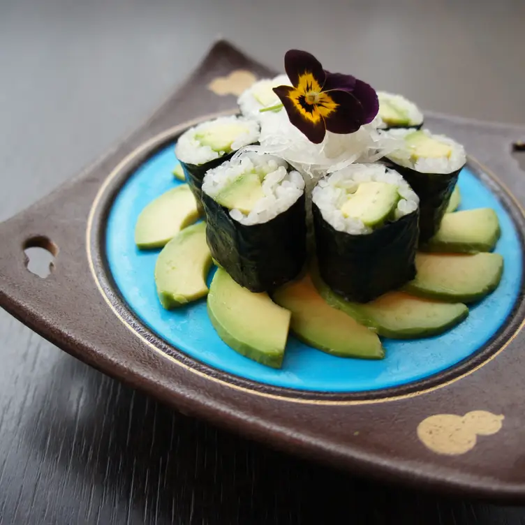 A small plate of six sushi rolls arranged like a flower on a bed of avocado at Sushi Murasaki, one of the best sushi restaurants in London.