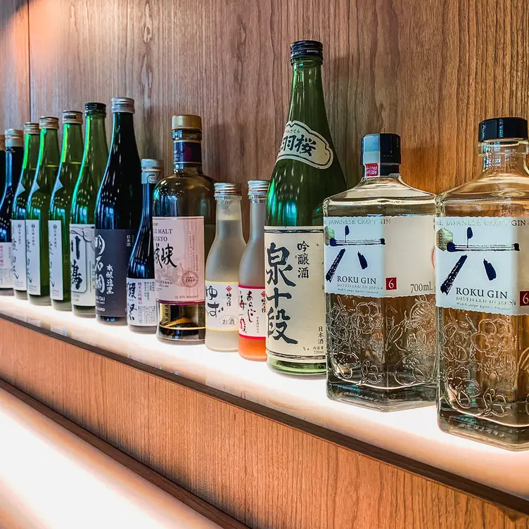 A shelf of alcohol bottles including sake and gin at Maido Sushi, one of the best sushi restaurants in London.