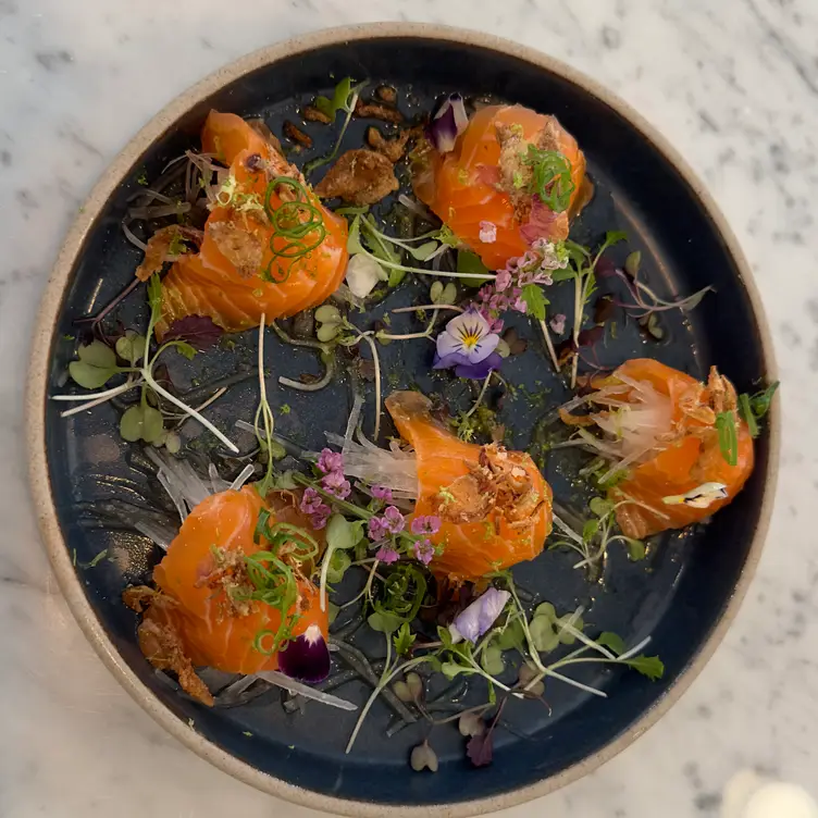 A dish of salmon sashimi garnished with fresh herbs at 103 Parkway, one of the best sushi restaurants in London.