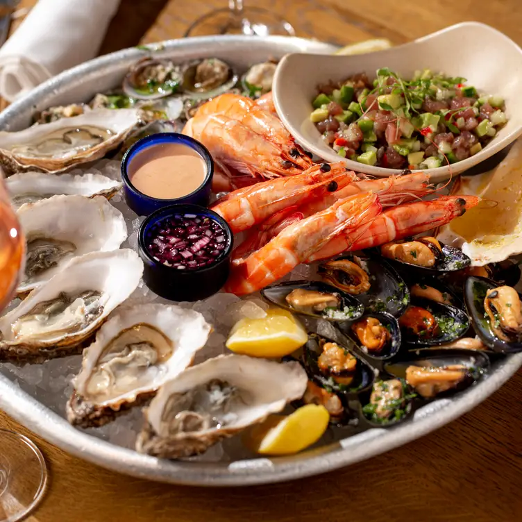 A seafood platter with garnish and lemons served with wine at Fish Market, one of the best seafood restaurants in London.