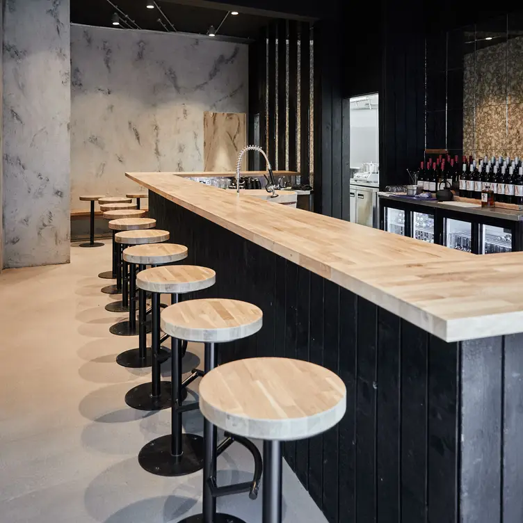 A modern bar and stool seating arrangement with a polished wooden finish at TEMAKI, one of the best sushi restaurants in London.