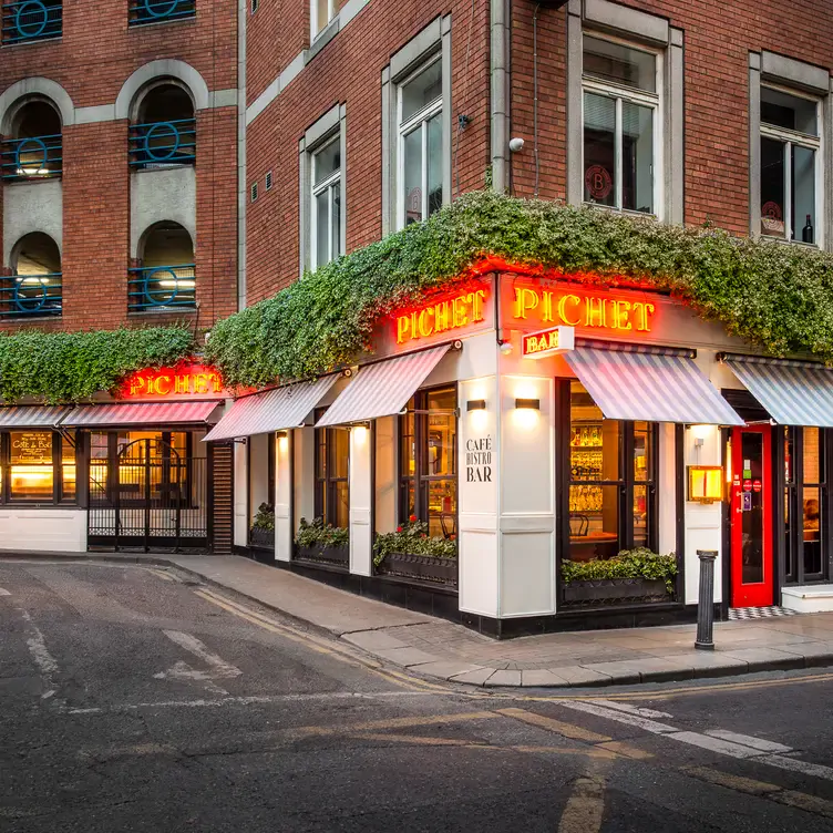 The exterior of Pichet, with neon-lit red signs and a bright red door.