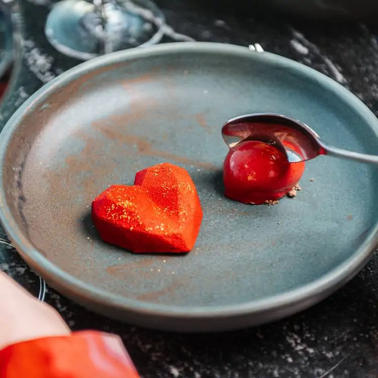 A heart-shaped dessert with red coating and sorbet, served at one of the best romantic restaurants in Manchester.