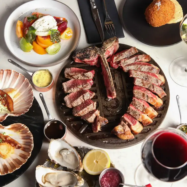 A spread of dishes featuring a tomahawk, oysters, scallops, salads and wine at Chop House Market Street, a restaurant in Edinburgh