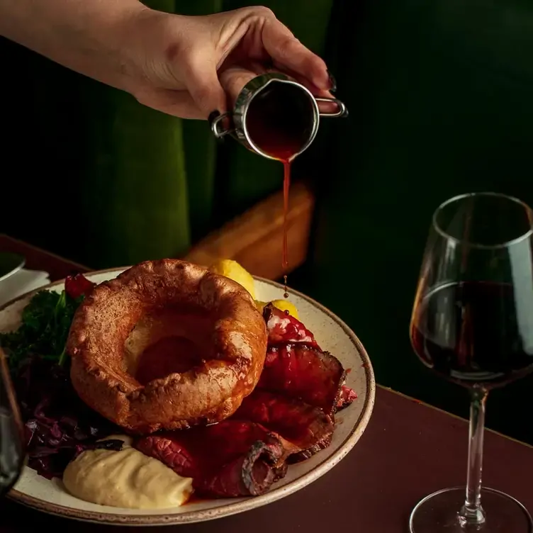 A hand pours gravy over a roasted beef dish at temper, one of the best new restaurants in London.