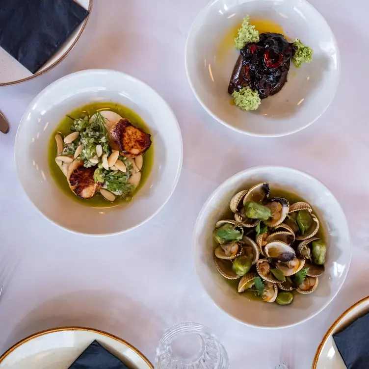 Three seafood dishes sit on a table at KELP, one of the best romantic restaurants in Glasgow.