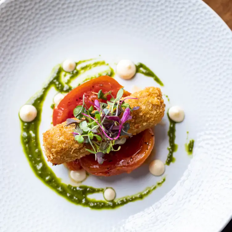 A fried dish plated on top of a roasted tomato at Bon Appetit, one of the best romantic restaurants in Dublin.