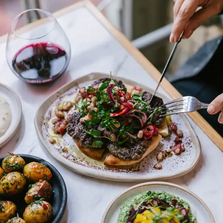 A diner tucking into their meal with a glass of red wine at Zahter.